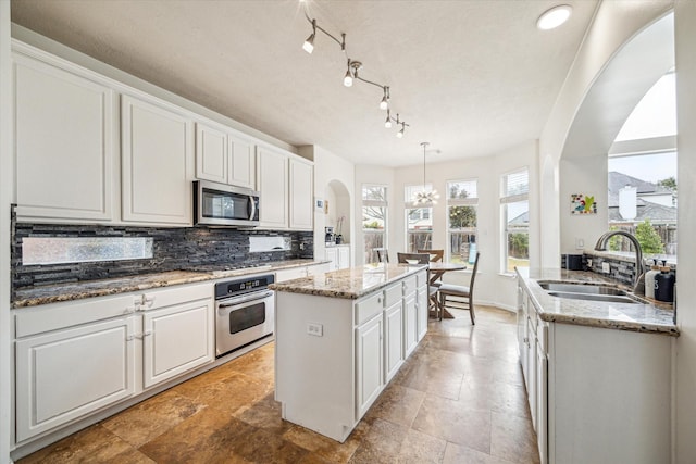 kitchen with sink, decorative light fixtures, appliances with stainless steel finishes, white cabinets, and backsplash