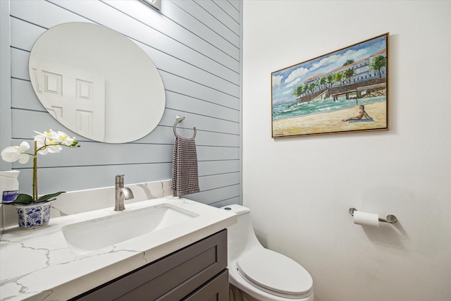 bathroom featuring vanity, toilet, and wood walls