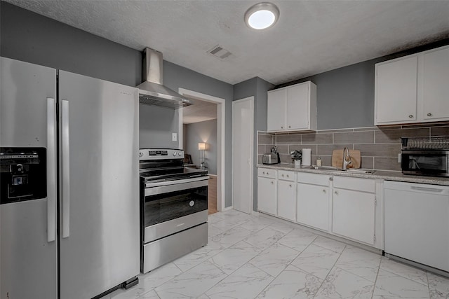 kitchen with wall chimney exhaust hood, sink, white cabinetry, appliances with stainless steel finishes, and decorative backsplash