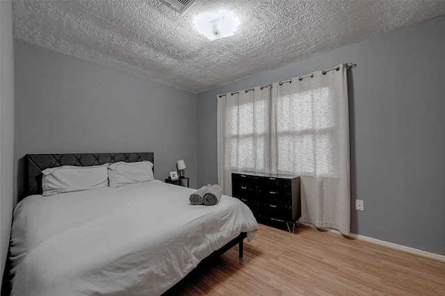 bedroom featuring a textured ceiling and light hardwood / wood-style floors