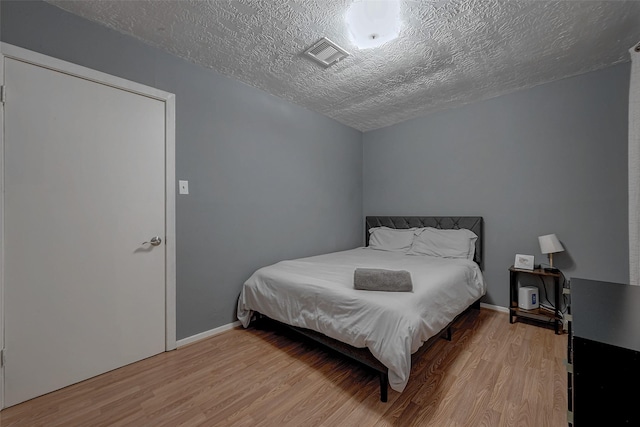 bedroom with a textured ceiling and light hardwood / wood-style floors