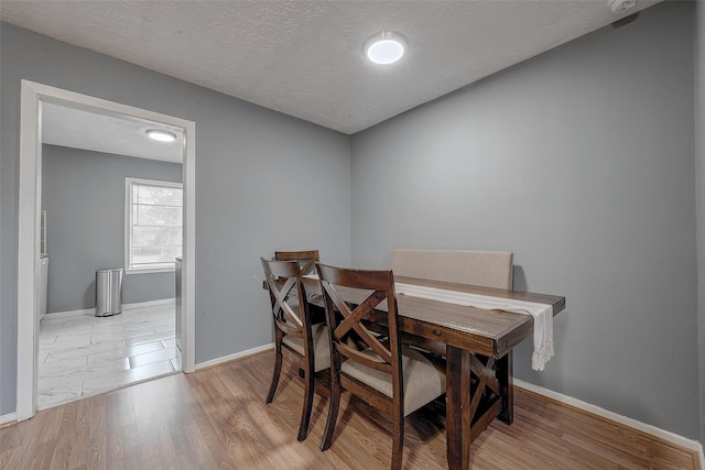 dining space featuring light hardwood / wood-style floors and a textured ceiling