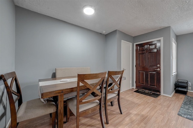 dining area featuring a textured ceiling and light hardwood / wood-style flooring