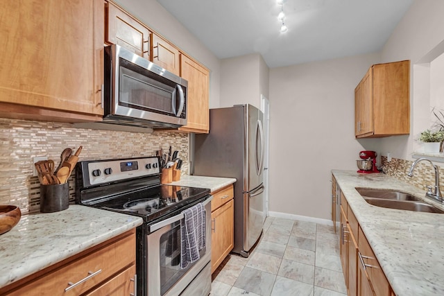 kitchen featuring light stone counters, appliances with stainless steel finishes, sink, and decorative backsplash