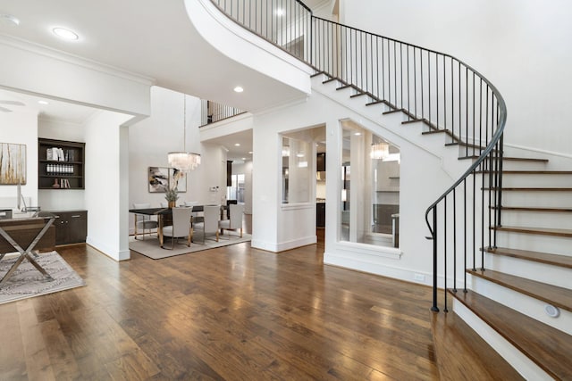 entryway featuring a notable chandelier, crown molding, dark hardwood / wood-style floors, and a high ceiling