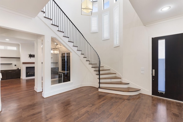 foyer with a wealth of natural light, ornamental molding, and dark hardwood / wood-style floors