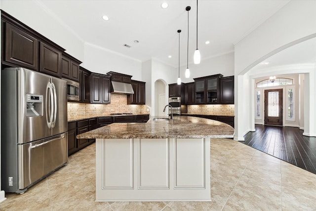 kitchen with appliances with stainless steel finishes, ventilation hood, an island with sink, sink, and light tile patterned floors