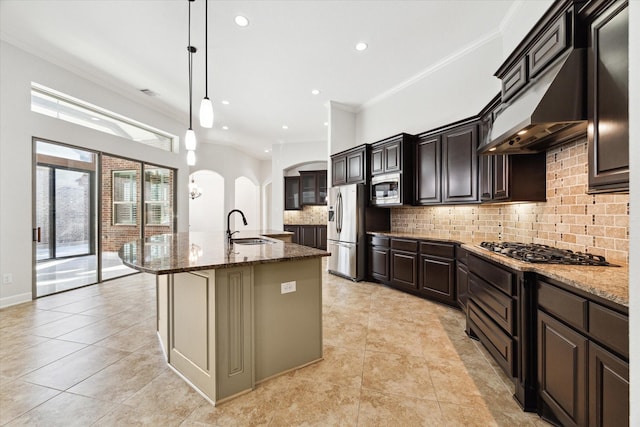 kitchen with pendant lighting, sink, appliances with stainless steel finishes, tasteful backsplash, and a center island with sink