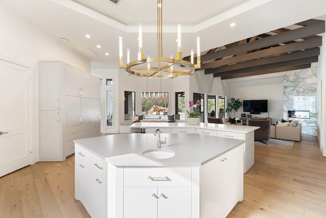 kitchen featuring white cabinetry, sink, a kitchen island with sink, and light hardwood / wood-style flooring