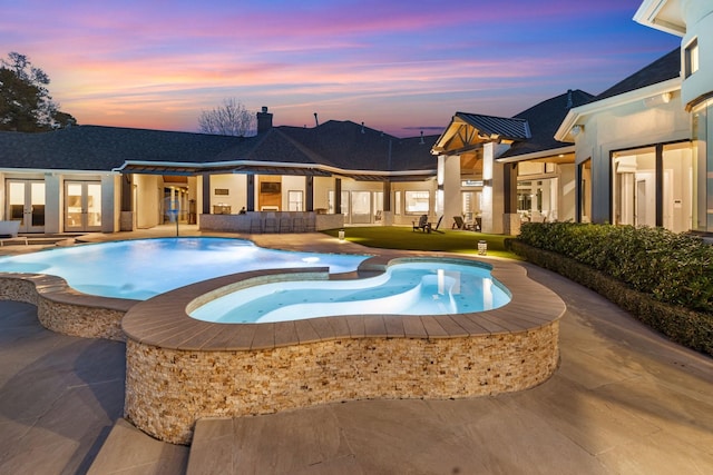 pool at dusk featuring a patio