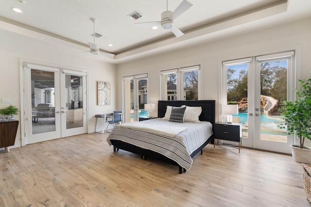 bedroom with a tray ceiling, access to outside, and french doors