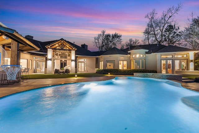 pool at dusk with a patio area