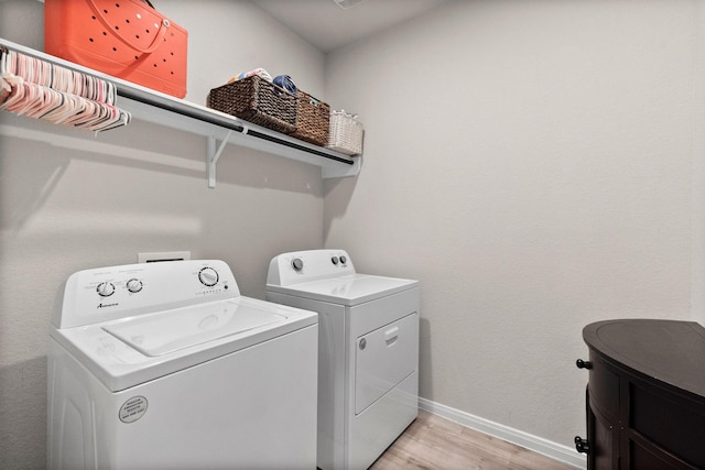 laundry room with washing machine and dryer and light hardwood / wood-style flooring