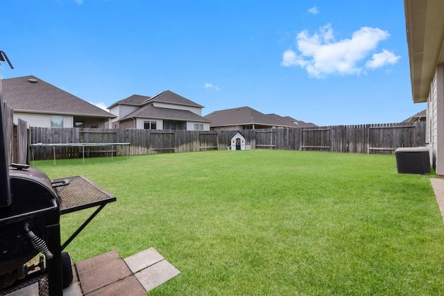 view of yard with a trampoline and central air condition unit