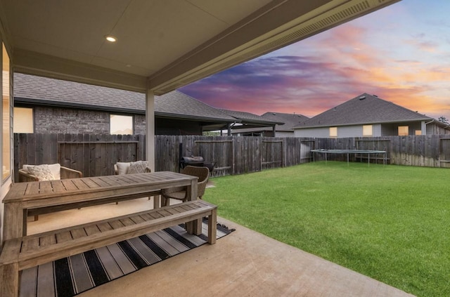 yard at dusk with a trampoline and a patio area