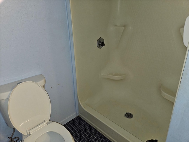 bathroom featuring tile patterned floors, toilet, and a shower