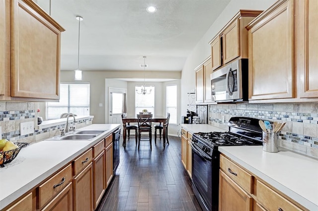 kitchen featuring sink, a wealth of natural light, black appliances, dark hardwood / wood-style flooring, and decorative light fixtures