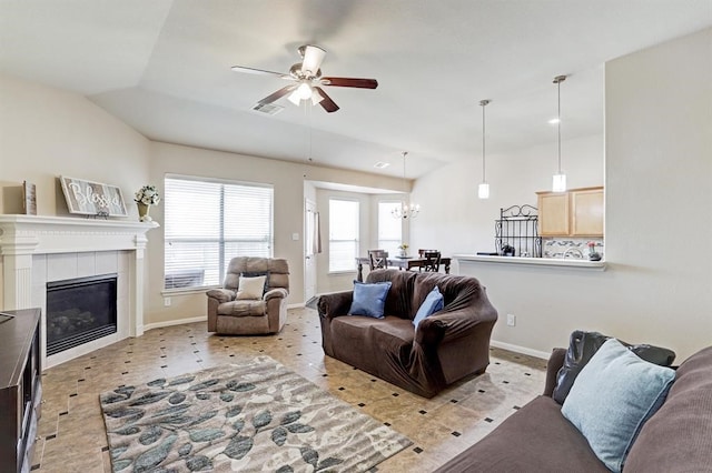 living room featuring ceiling fan, a fireplace, and vaulted ceiling