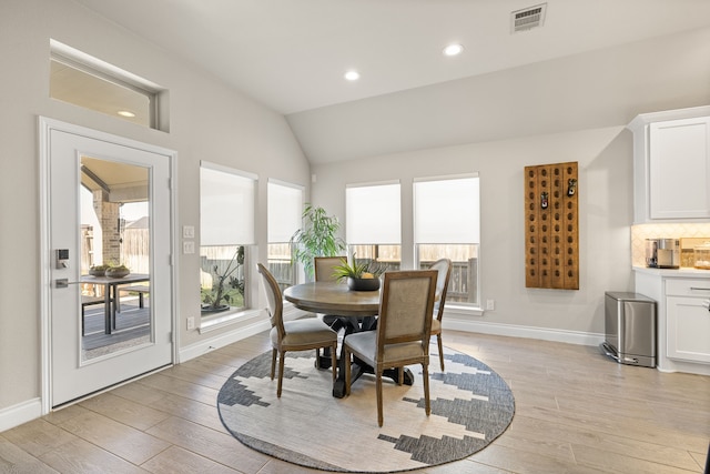 dining space with vaulted ceiling and light wood-type flooring