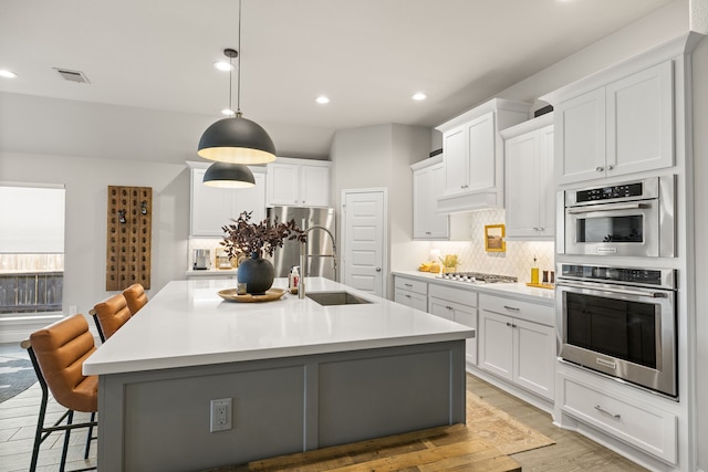 kitchen featuring a kitchen island with sink, a breakfast bar area, and white cabinets