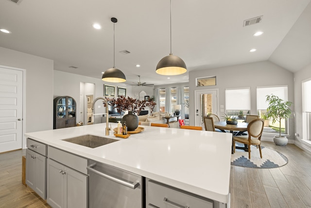 kitchen with sink, decorative light fixtures, a center island with sink, light wood-type flooring, and dishwasher