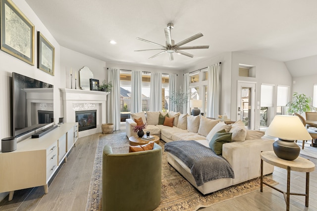 living room featuring lofted ceiling, ceiling fan, and light hardwood / wood-style flooring