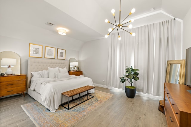 bedroom featuring light hardwood / wood-style flooring, a notable chandelier, and vaulted ceiling