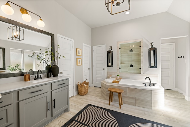 bathroom featuring lofted ceiling, shower with separate bathtub, vanity, and a notable chandelier