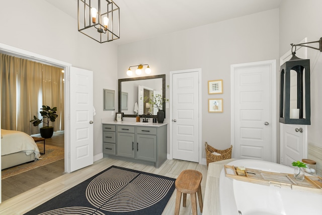 bathroom with hardwood / wood-style flooring, vanity, a notable chandelier, and a tub to relax in