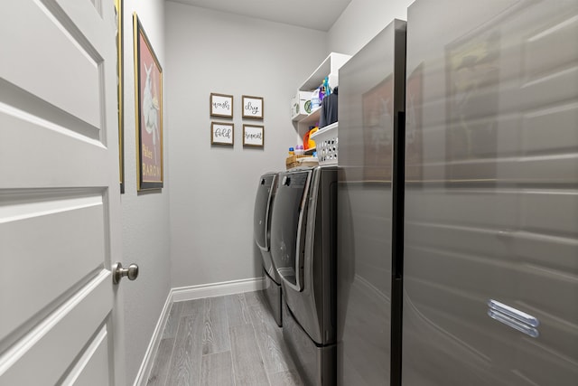 laundry area with light hardwood / wood-style floors and washer and dryer