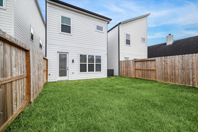 rear view of house featuring central AC and a lawn