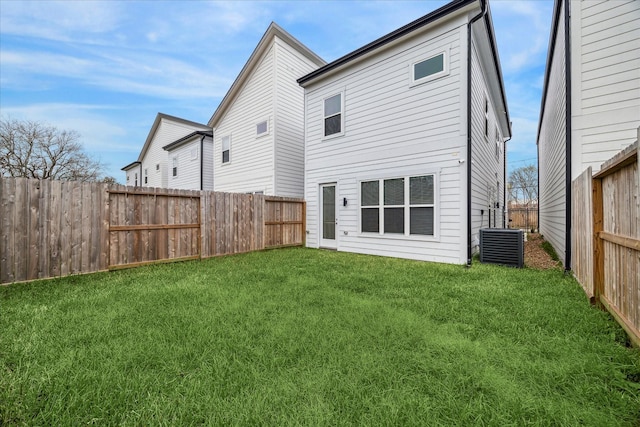 rear view of house featuring central air condition unit and a lawn