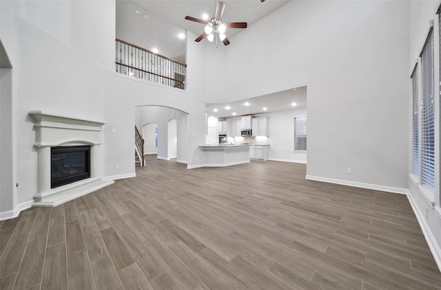 unfurnished living room featuring a high ceiling, dark hardwood / wood-style floors, and ceiling fan