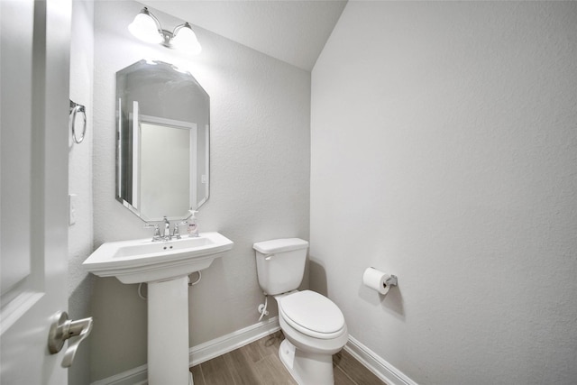 bathroom with hardwood / wood-style floors, vaulted ceiling, and toilet