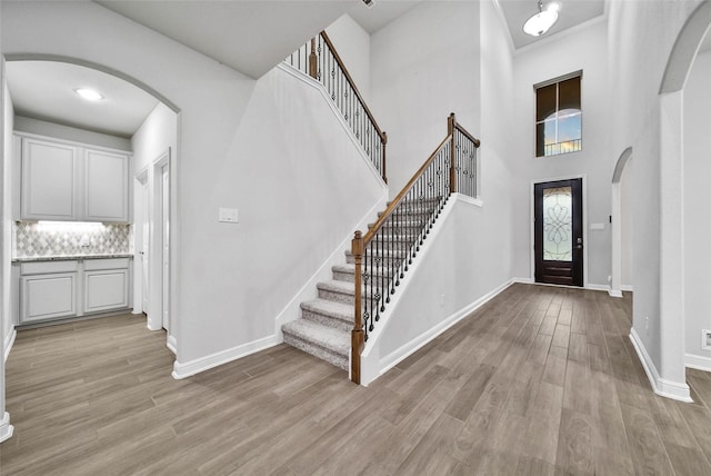 entryway featuring a high ceiling, crown molding, and light hardwood / wood-style flooring