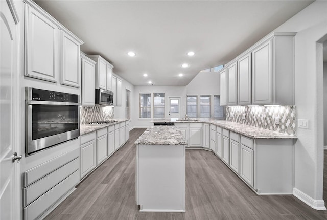 kitchen with white cabinetry, light stone countertops, a center island, and appliances with stainless steel finishes