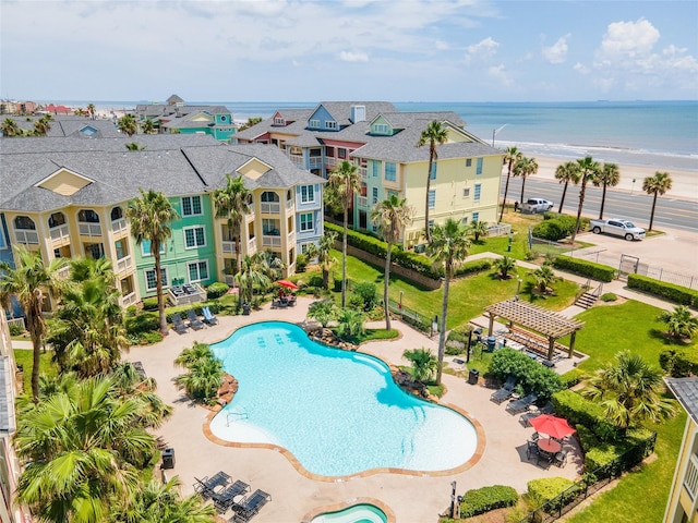 view of swimming pool with a water view, a view of the beach, a pergola, and a patio area