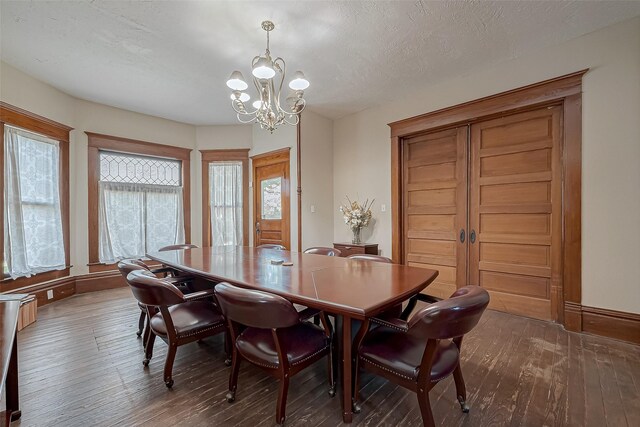 dining space featuring dark wood-type flooring, an inviting chandelier, and a textured ceiling