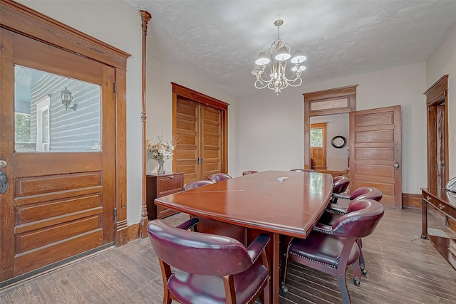 dining space with light hardwood / wood-style floors, a textured ceiling, and a notable chandelier