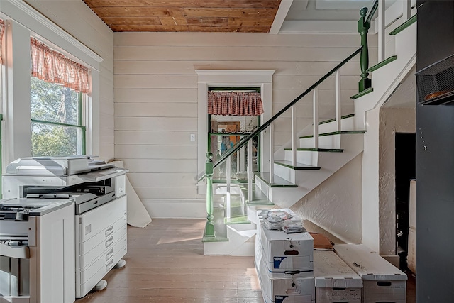 stairway with wood ceiling, wooden walls, and hardwood / wood-style floors