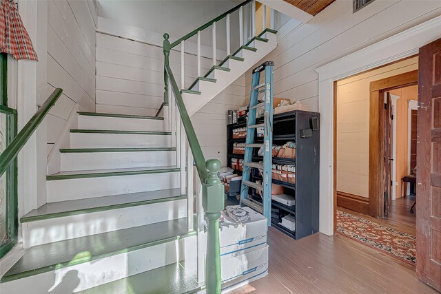 staircase with wooden walls and hardwood / wood-style floors