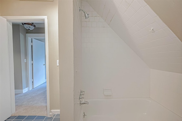 bathroom with lofted ceiling and tiled shower / bath