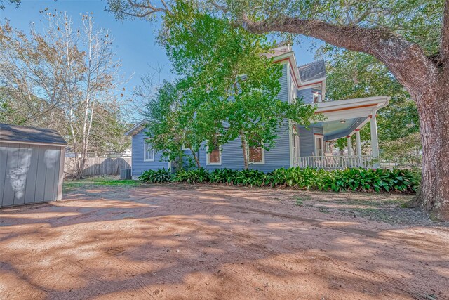 view of side of home with covered porch and a shed