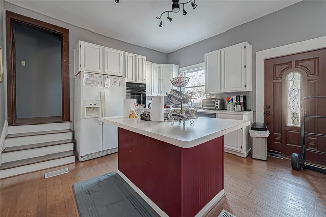 kitchen with white cabinetry, oven, a center island, white fridge with ice dispenser, and light wood-type flooring