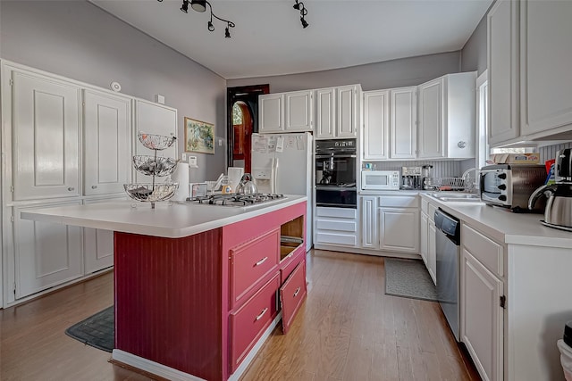 kitchen with white cabinets, stainless steel appliances, a sink, and light countertops