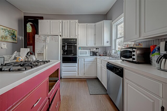 kitchen with white cabinetry, appliances with stainless steel finishes, light hardwood / wood-style floors, and sink