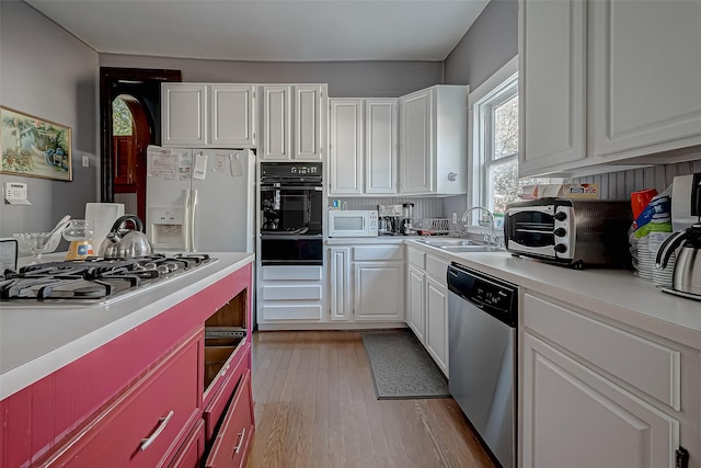 kitchen with white cabinets, appliances with stainless steel finishes, light countertops, and a sink