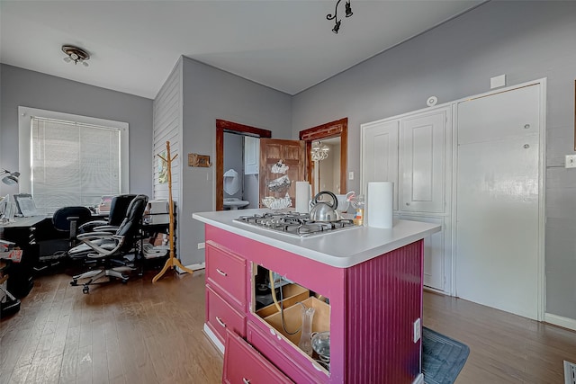 kitchen with light countertops, a kitchen island, wood finished floors, and stainless steel gas stovetop