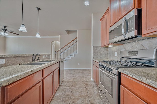 kitchen with sink, hanging light fixtures, ornamental molding, light tile patterned floors, and stainless steel appliances