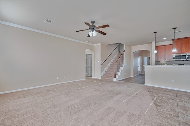 unfurnished living room with light colored carpet, ornamental molding, and ceiling fan